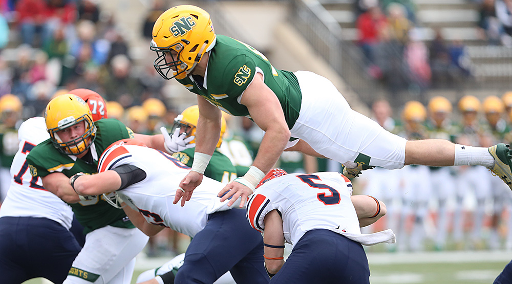 Matt Barrett takes flight over a would-be blocker from Macalester. (d3photography.com file photo by Steve Frommell)